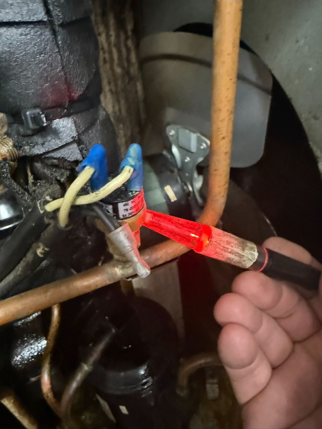 Professional leak detector device with reddish-orange indicator light on refrigeration equipment